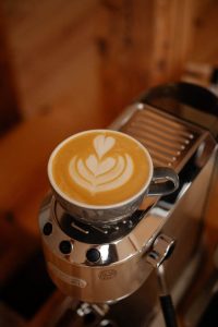 Kubek kawy latte z latte art na ekspresie ciśnieniowym, symbolizujący rozwój czwartej fali kawy i rosnącą popularność kawy specialty w domach.