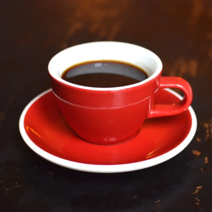 Kawa americano w czarwonej filiżance na drewnianym blacie