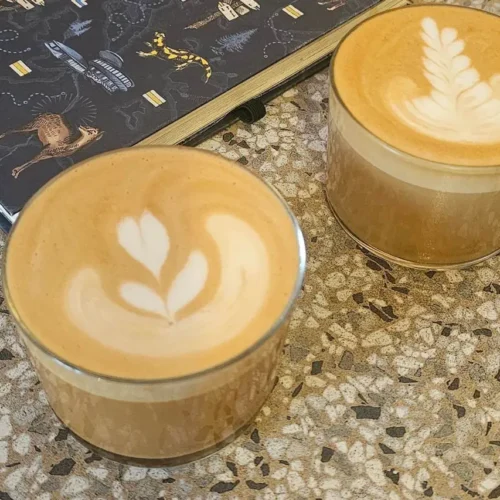 Dwa flat white z latte art w szklankach na stoliku w kawiarni Forum w Warszawie