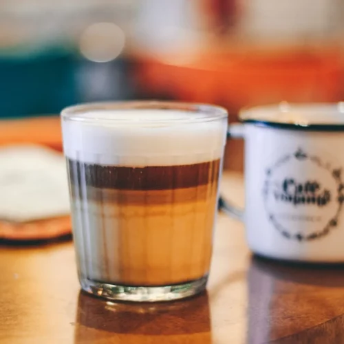 Caffè latte w wysokiej szklance z widocznymi warstwami mleka, espresso i pianki